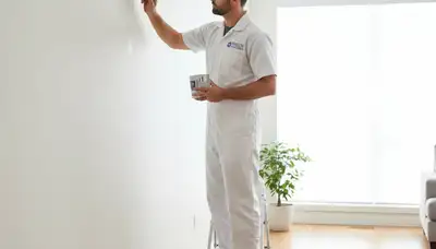 Painter applying paint touch-up service in Arlington, TX for faded and chipped wall repair
